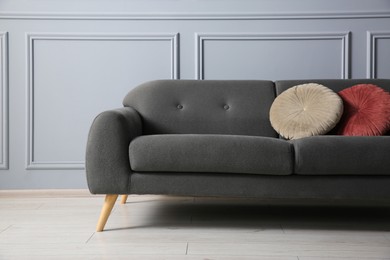 Stylish sofa with cushions near grey wall