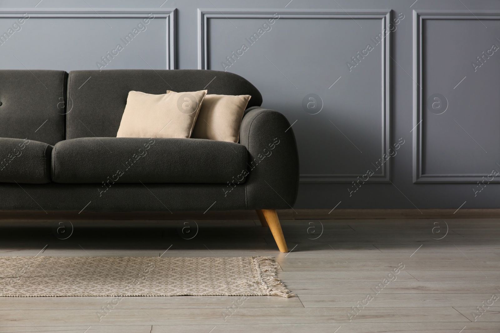 Photo of Stylish sofa with cushions near grey wall, space for text