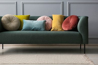 Photo of Stylish sofa with cushions near grey wall