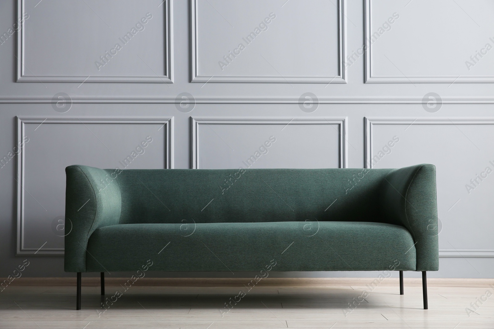 Photo of One stylish sofa near grey wall indoors