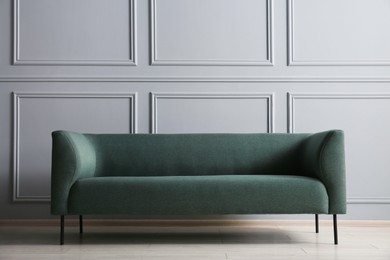 One stylish sofa near grey wall indoors