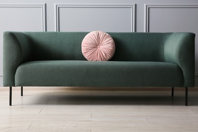 Photo of Stylish sofa with cushion near grey wall