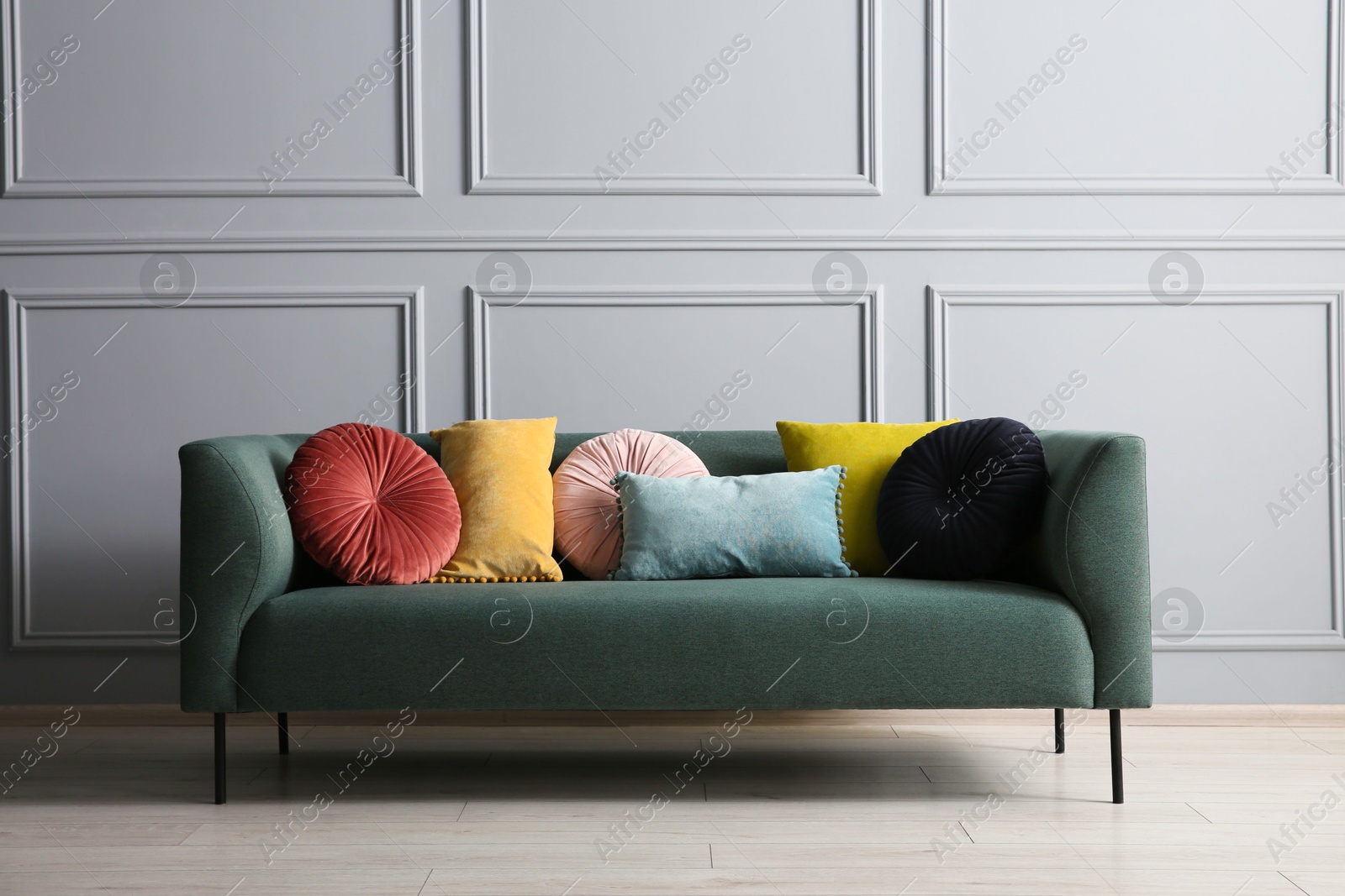 Photo of Stylish sofa with different cushions near grey wall