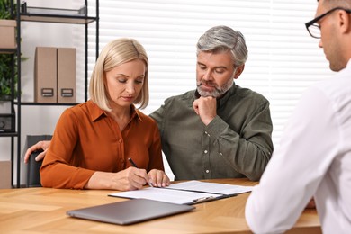 Photo of Pension plan. Couple consulting with insurance agent at table indoors