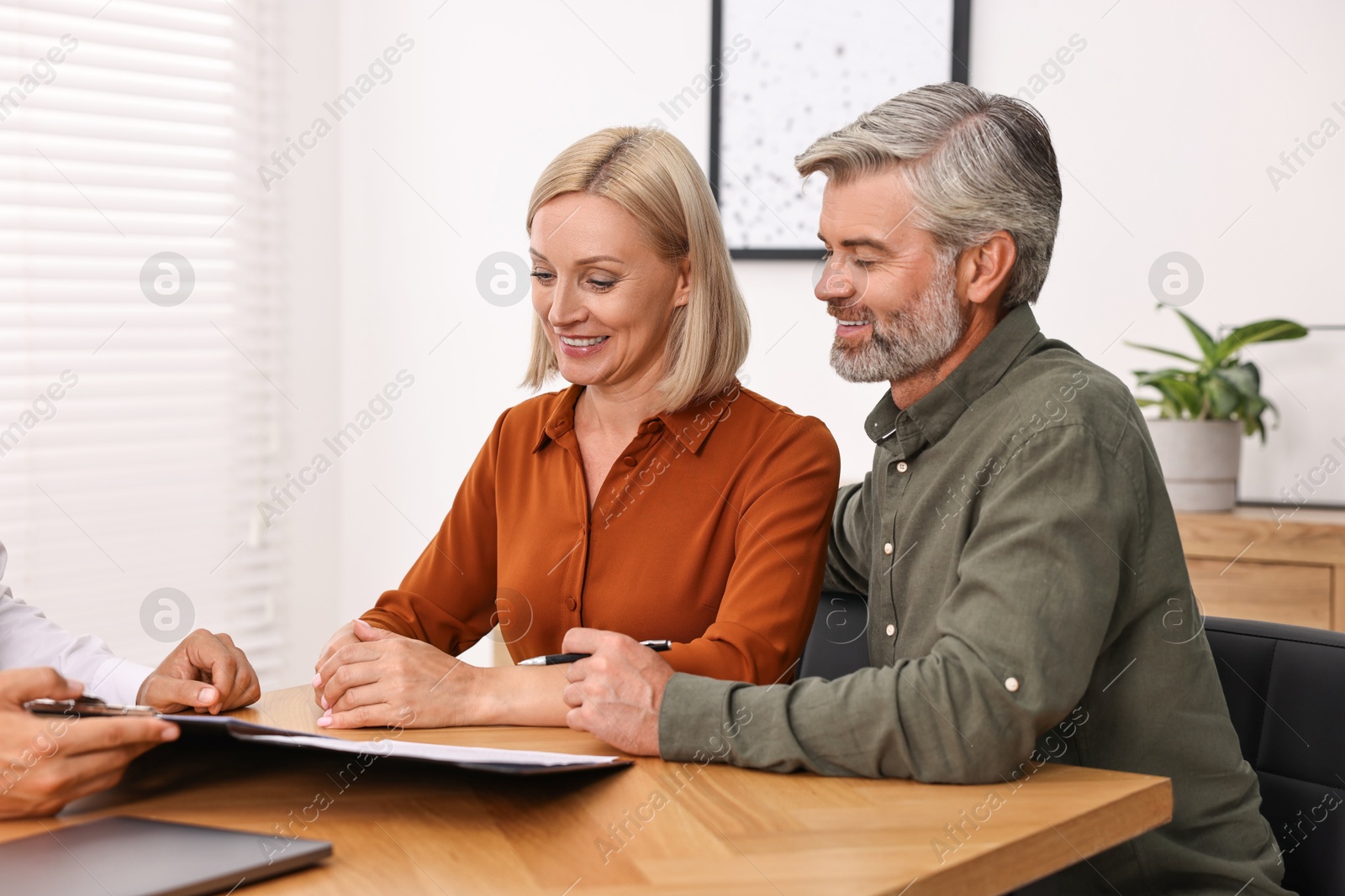 Photo of Pension plan. Couple consulting with insurance agent at table indoors