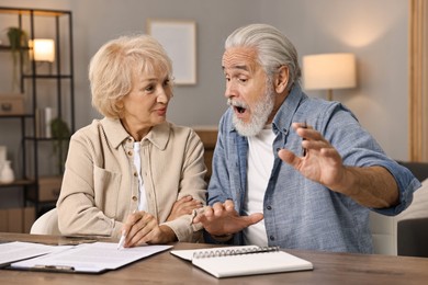 Photo of Pension savings. Senior couple planning budget at wooden table indoors