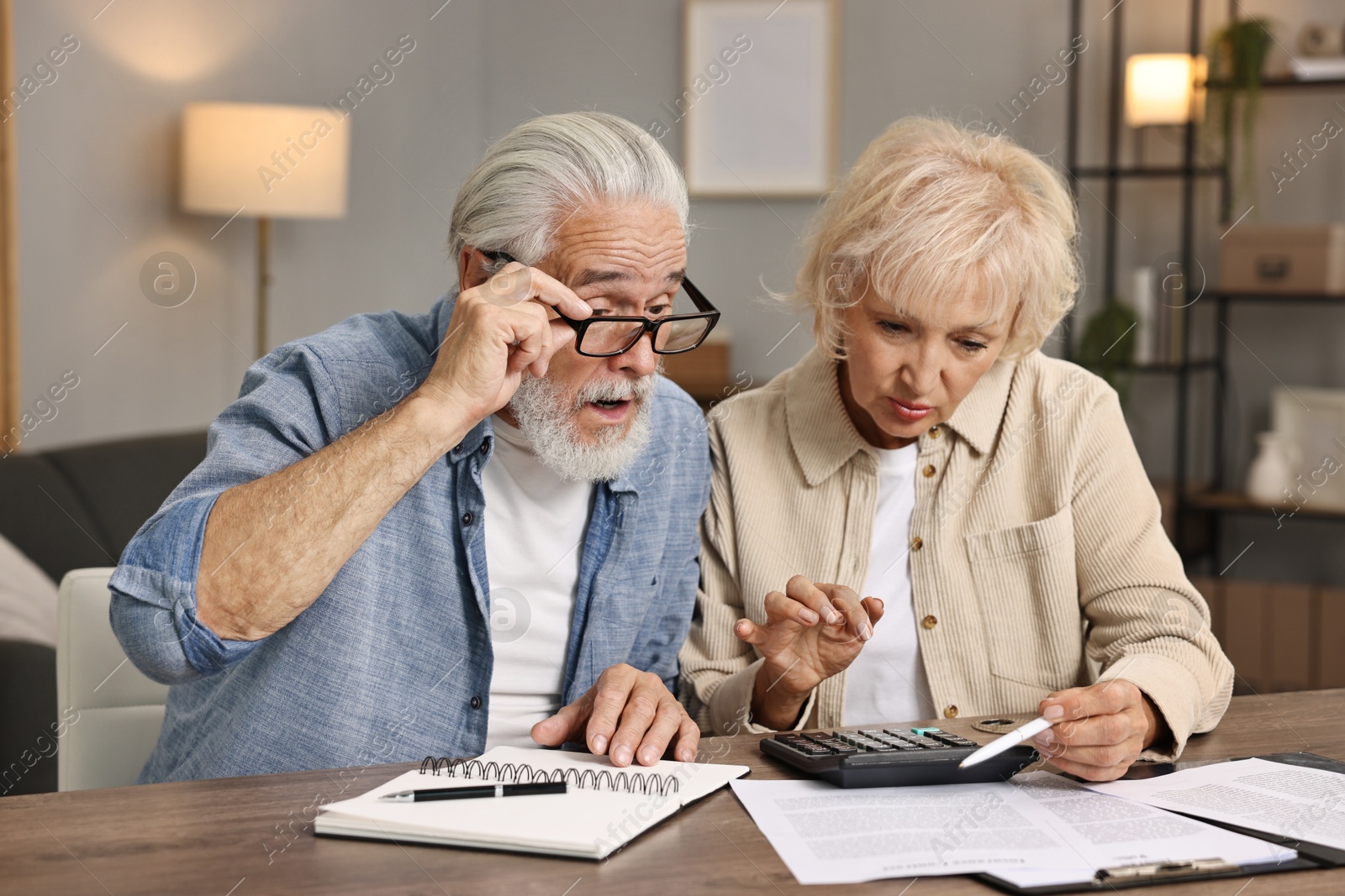 Photo of Pension savings. Senior couple planning budget at wooden table indoors