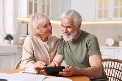 Photo of Pension savings. Senior couple planning budget at wooden table indoors