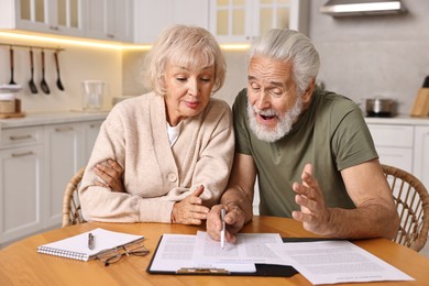 Photo of Pension savings. Senior couple planning budget at wooden table indoors