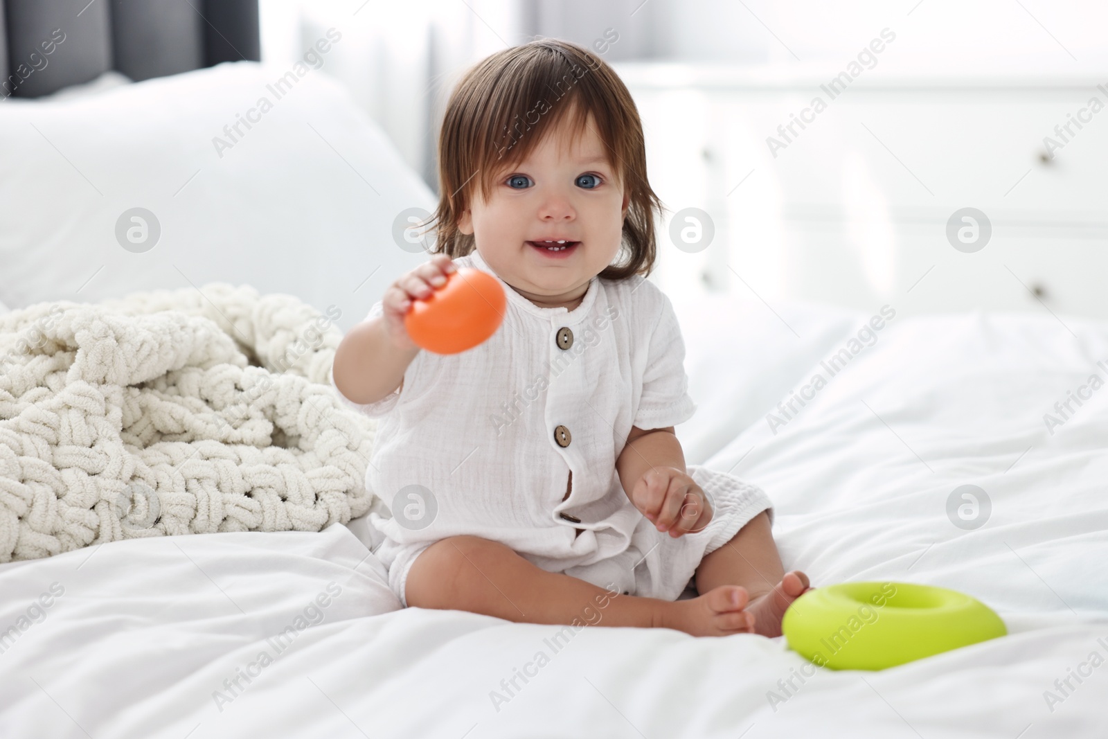 Photo of Cute little baby with toys on bed at home