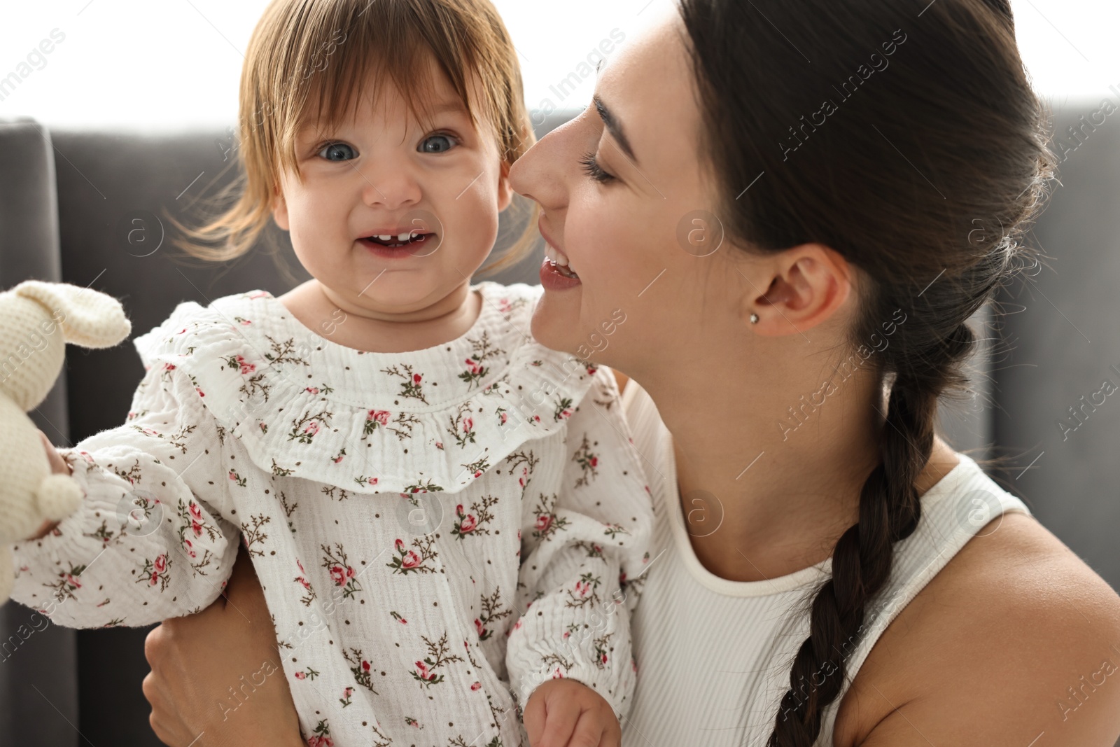 Photo of Beautiful young mother and her cute little baby with rabbit toy indoors