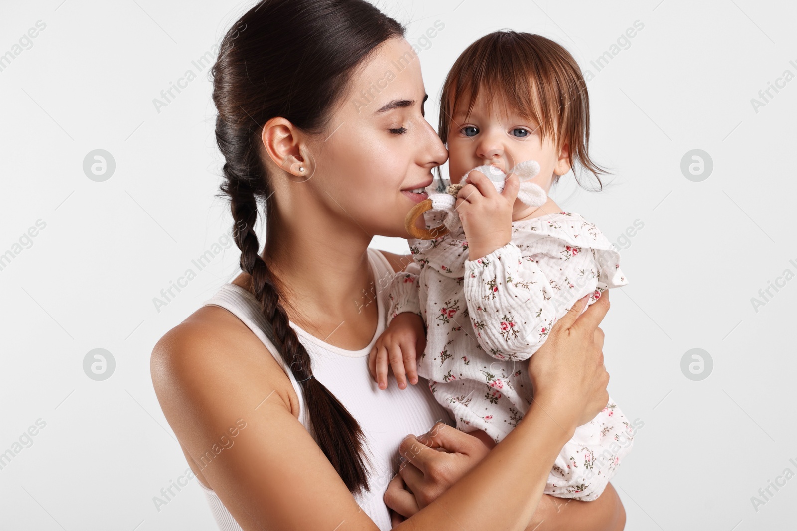 Photo of Beautiful young mother and her cute little baby with rattle on light grey background