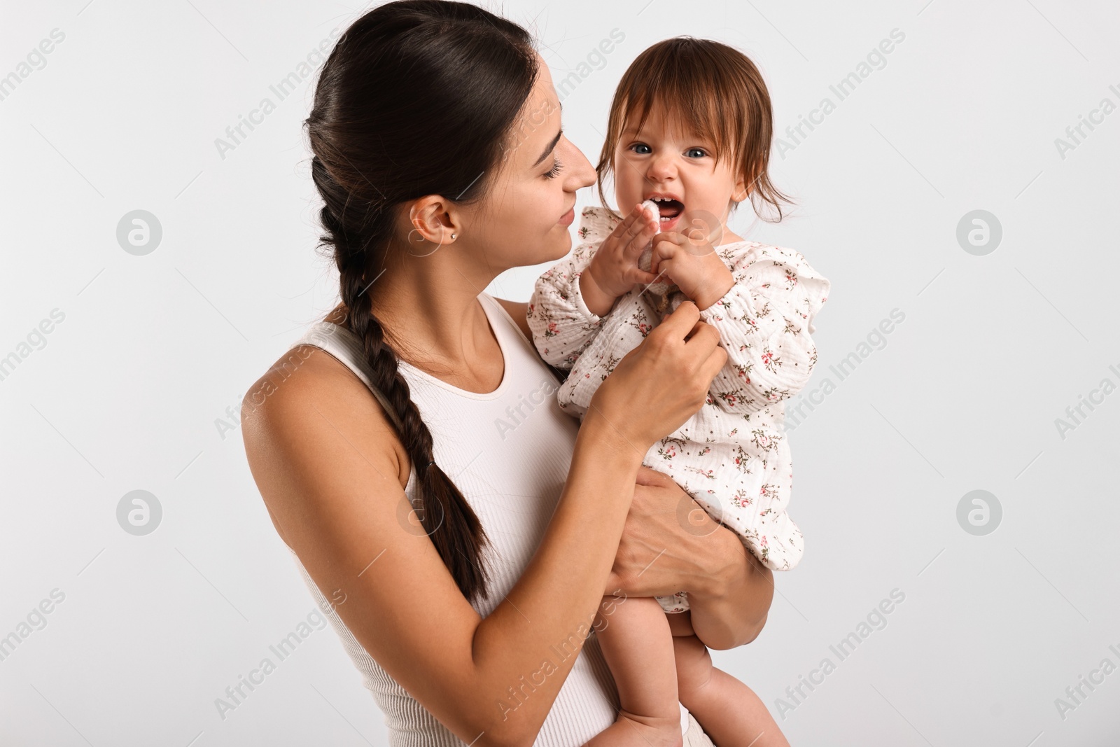 Photo of Beautiful young mother and her cute little baby with rattle on light grey background