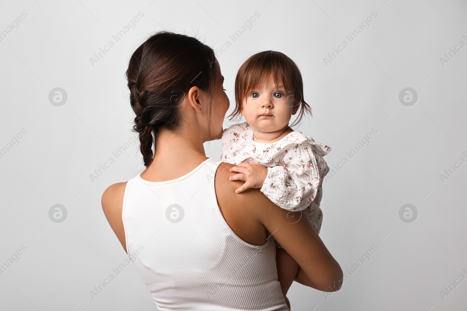 Photo of Beautiful young mother and her cute little baby on light grey background