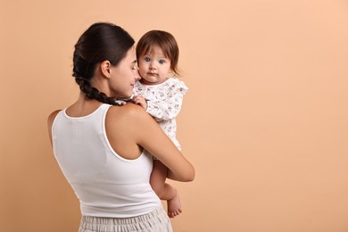 Photo of Beautiful young mother and her cute little baby on beige background, space for text