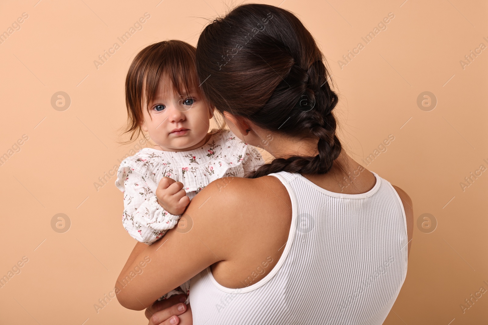 Photo of Beautiful young mother and her cute little baby on beige background