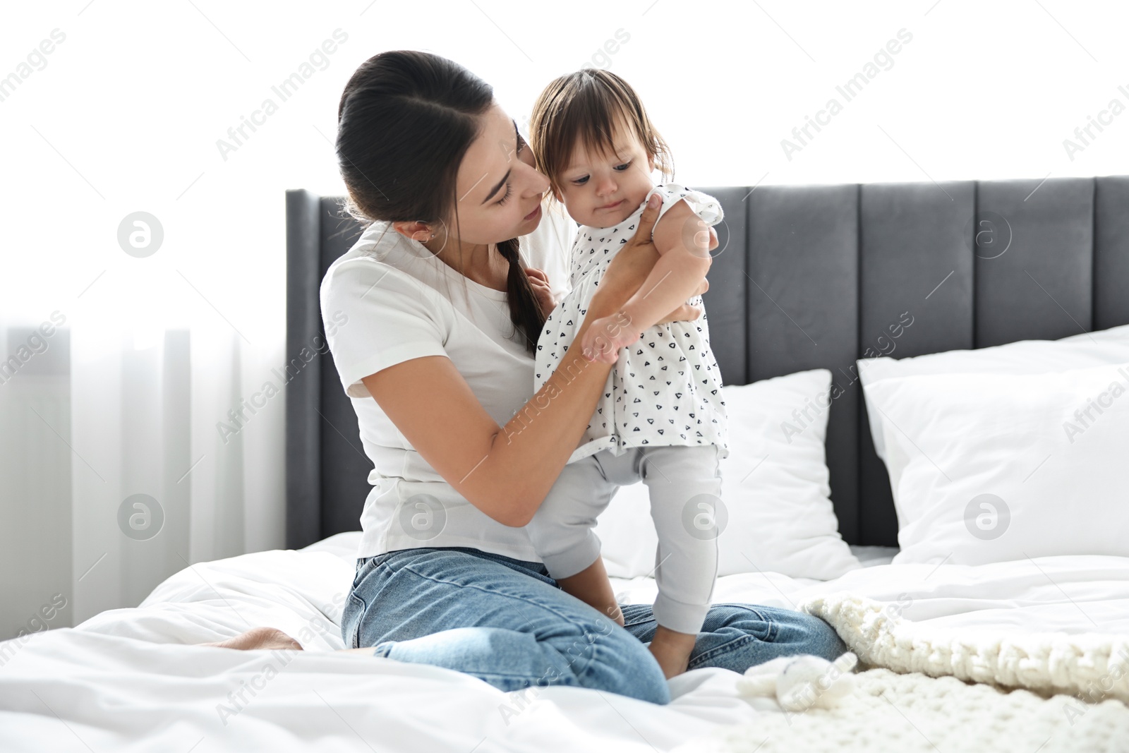 Photo of Beautiful young mother and her cute little baby on bed at home