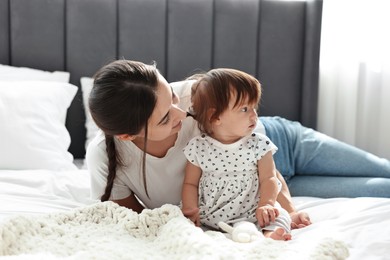 Beautiful young mother and her cute little baby on bed at home