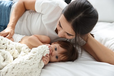 Beautiful young mother with her cute little baby on bed