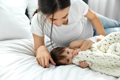 Beautiful young mother with her cute little baby on bed