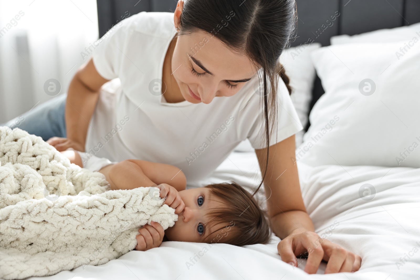 Photo of Beautiful young mother with her cute little baby on bed