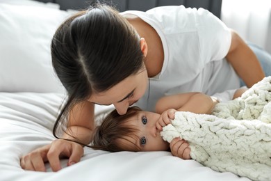 Beautiful young mother with her cute little baby on bed