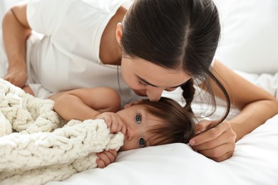 Beautiful young mother with her cute little baby on bed