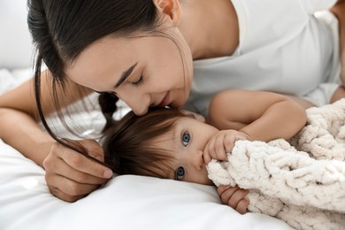 Photo of Beautiful young mother with her cute little baby on bed