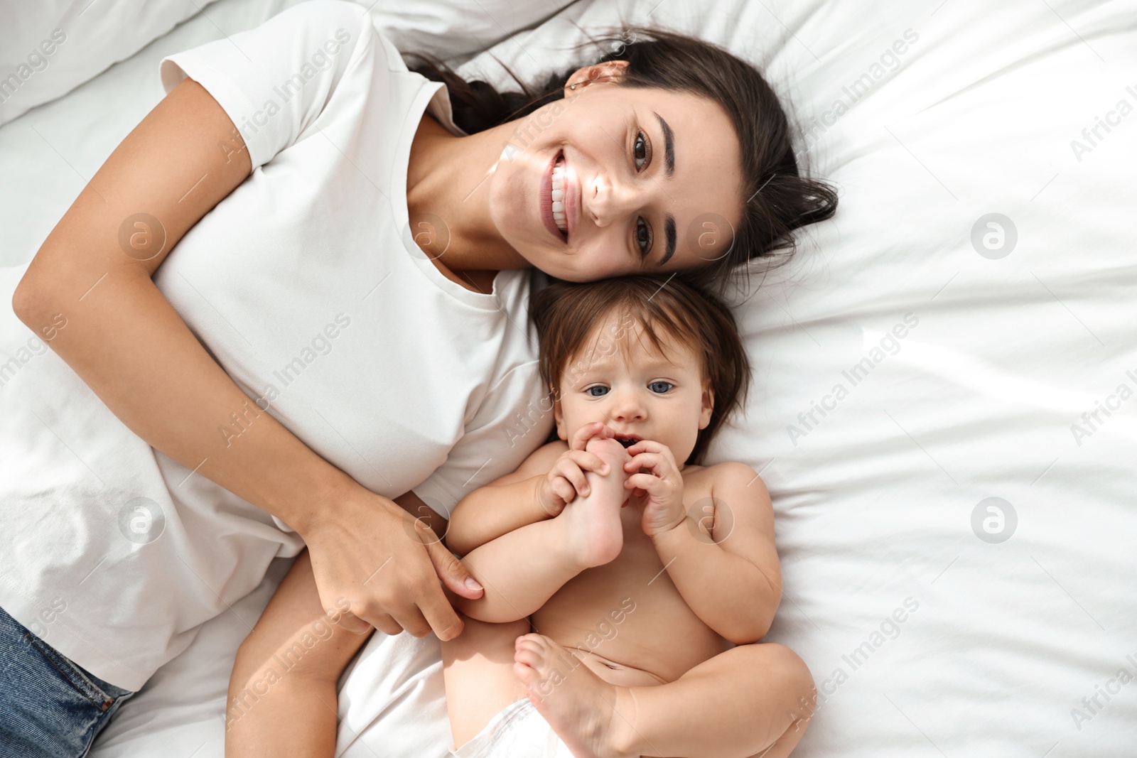 Photo of Beautiful young mother with her cute little baby on bed