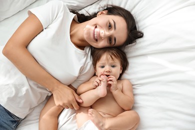 Beautiful young mother with her cute little baby on bed