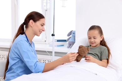 Photo of Doctor examining little girl on bed at hospital