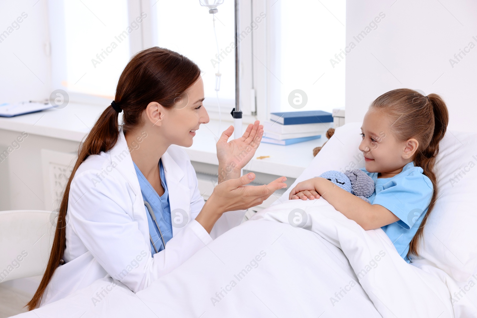 Photo of Doctor examining little girl on bed at hospital