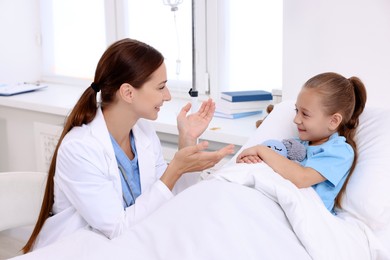 Photo of Doctor examining little girl on bed at hospital