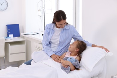 Mother and her little daughter on bed in hospital