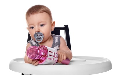 Cute little baby with pacifier and microphone in high chair on white background