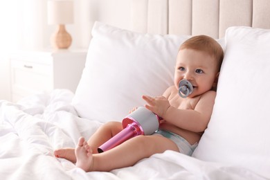 Cute little baby with microphone and pacifier on bed at home, space for text