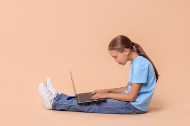 Girl with incorrect posture and laptop sitting on beige background