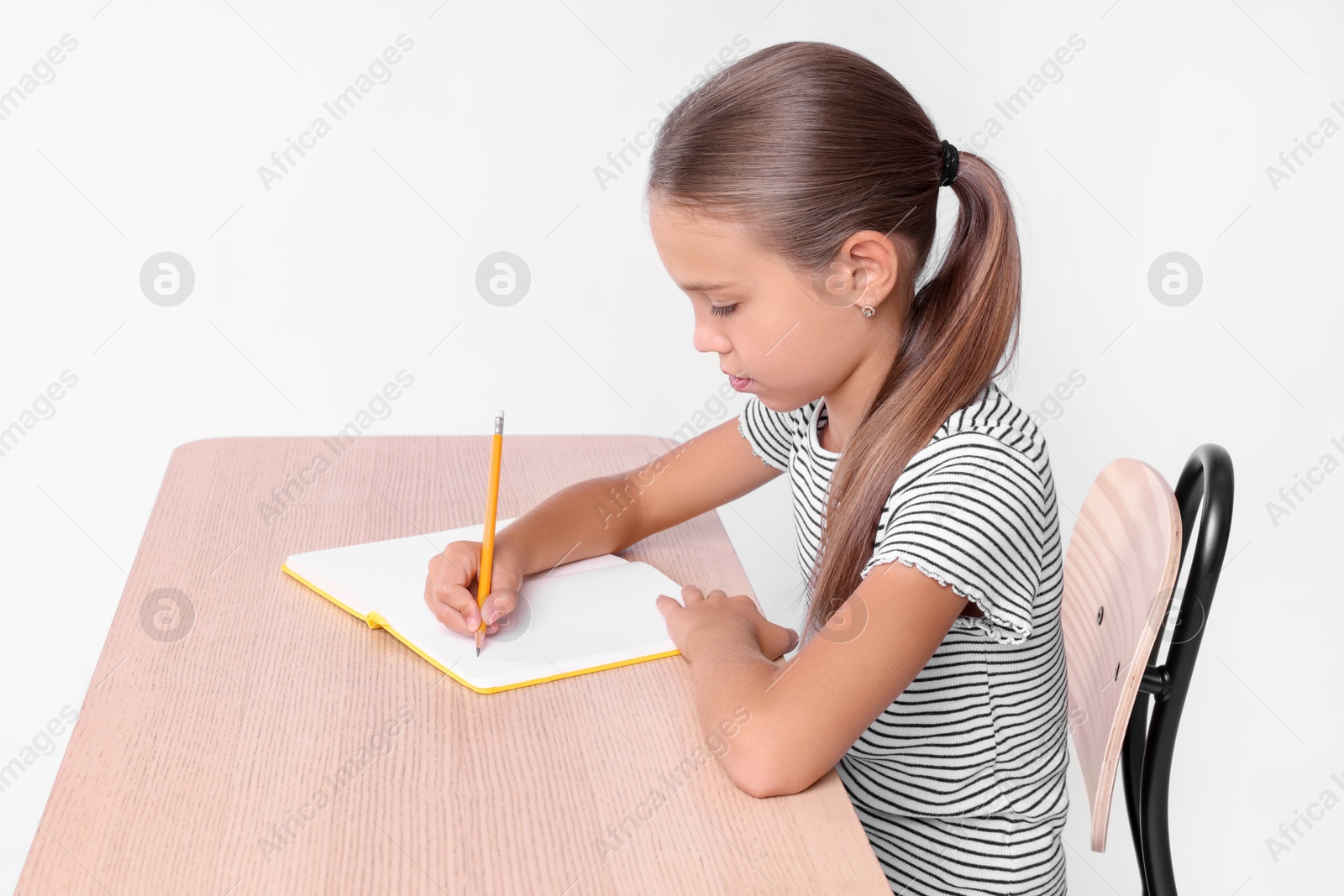 Photo of Girl with correct posture and notebook sitting at wooden desk on white background