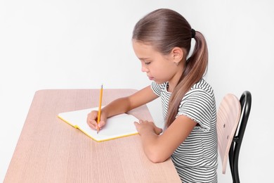 Girl with correct posture and notebook sitting at wooden desk on white background