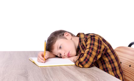 Boy with incorrect posture and notebook at wooden desk on white background