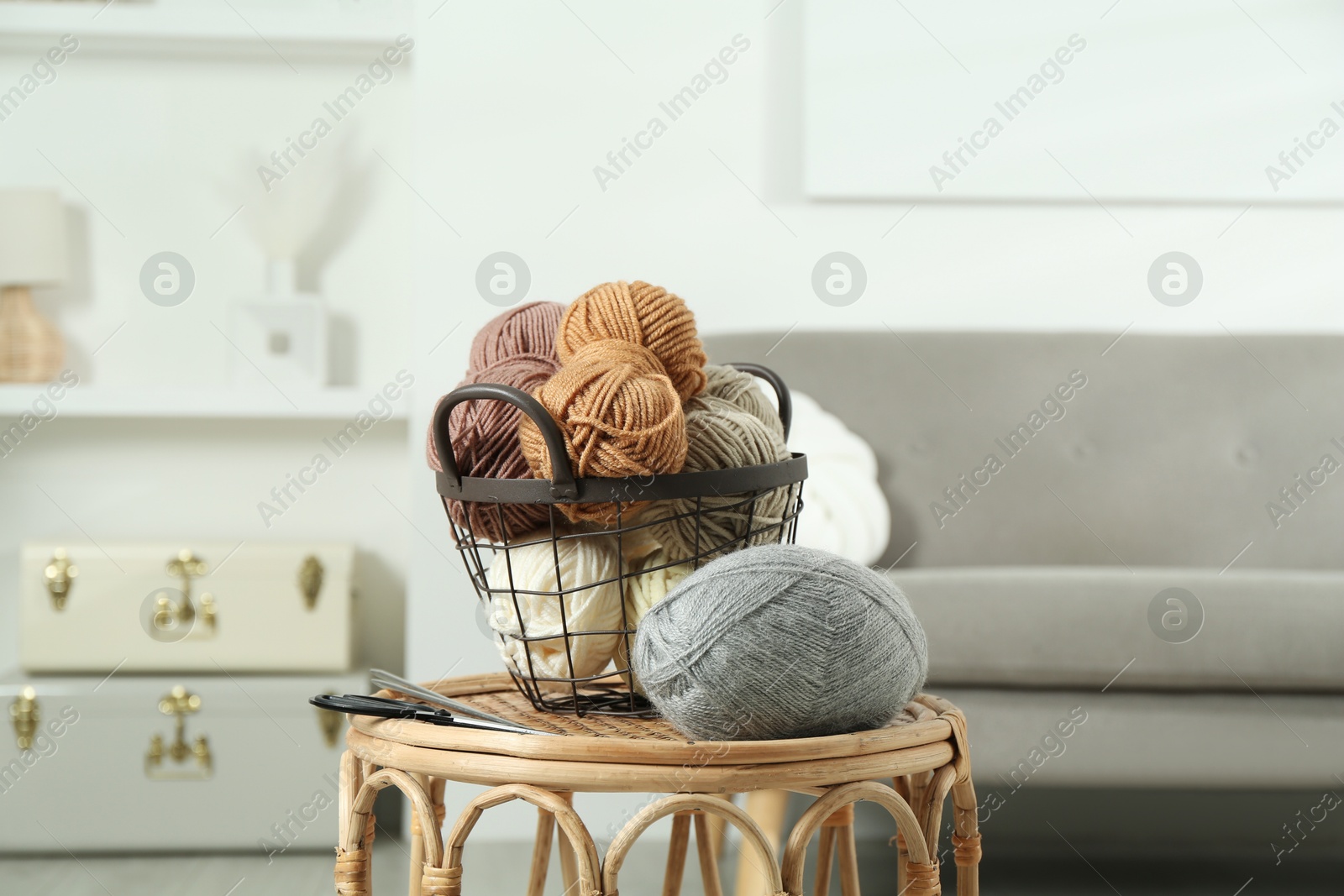 Photo of Skeins of soft yarn, knitting needles and scissors on table indoors