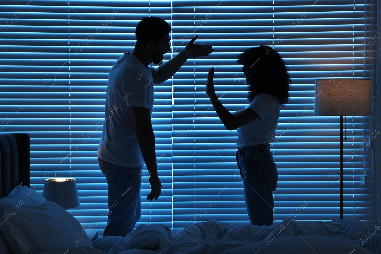 Photo of Emotional couple arguing in bedroom at night. Relationship problems