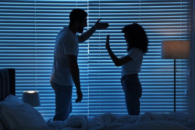 Emotional couple arguing in bedroom at night. Relationship problems