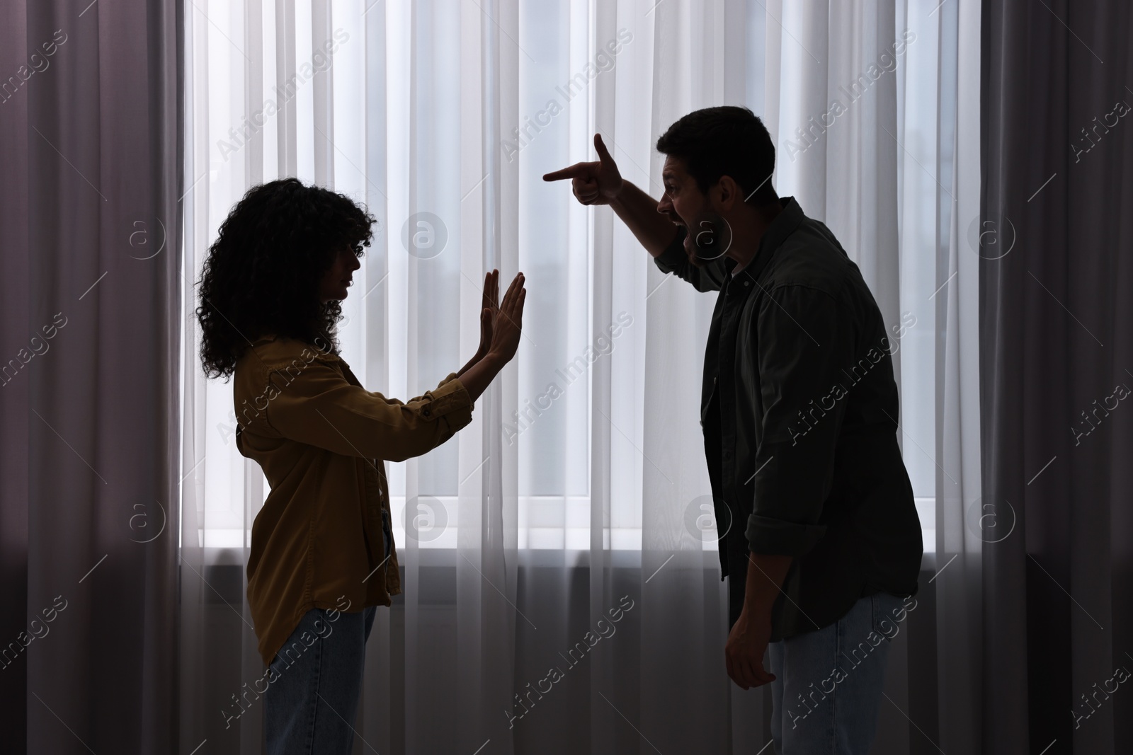 Photo of Emotional couple arguing indoors at night. Relationship problems