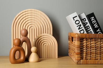 Photo of Different decorative elements and hardcover books with city names on wooden table near gray wall indoors