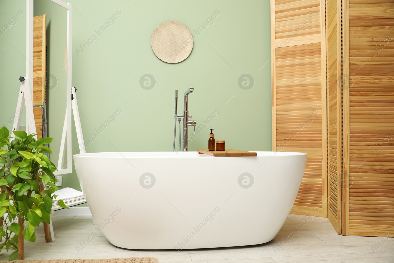 Photo of Stylish bathroom interior with folding screen and tub