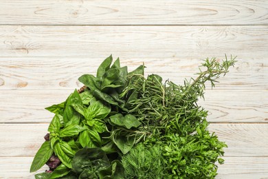 Photo of Different fresh herbs in basket on white wooden table, top view. Space for text