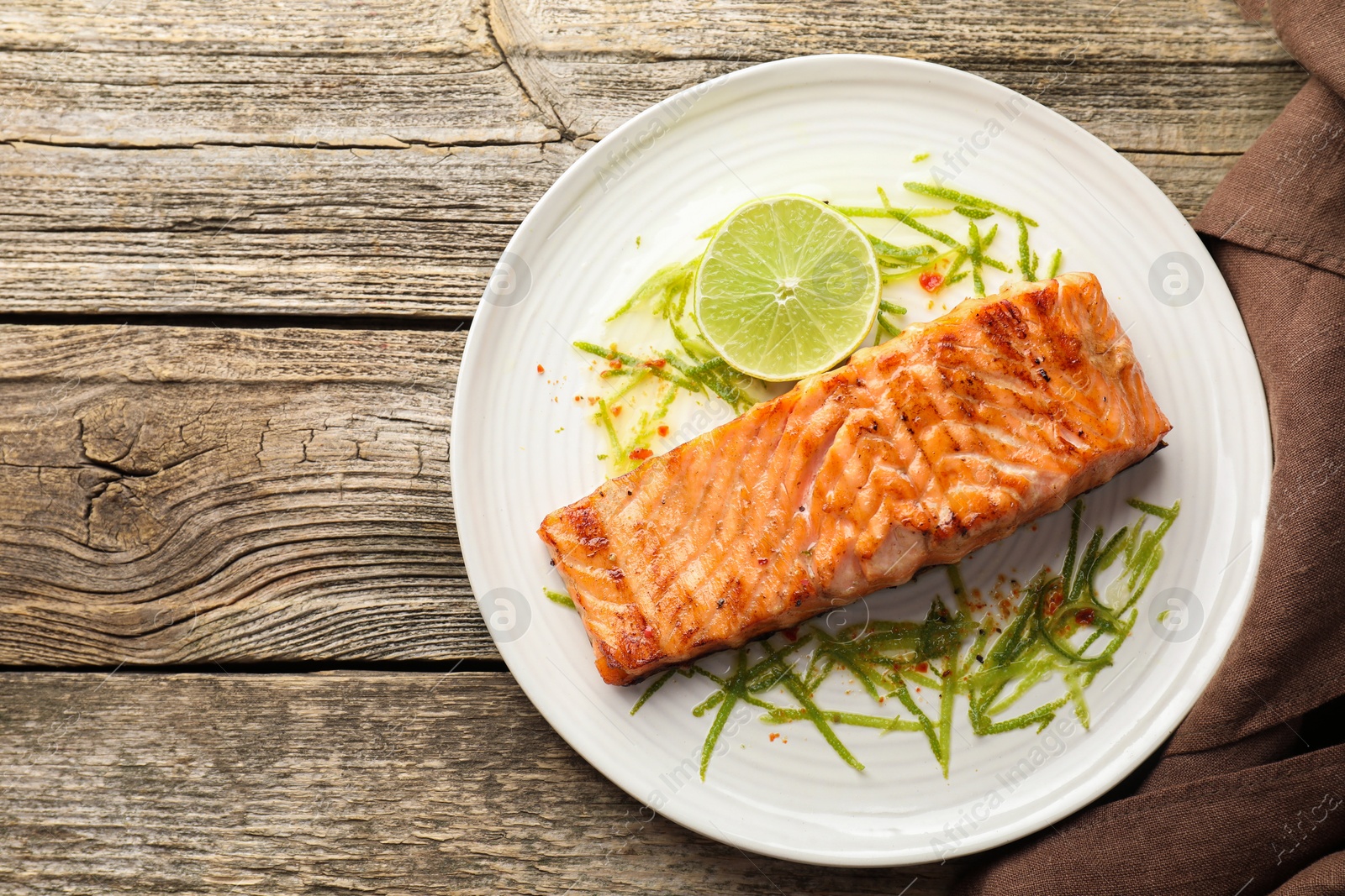 Photo of Delicious grilled salmon fillet served on wooden table, top view. Space for text