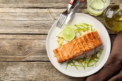 Photo of Delicious grilled salmon fillet served on wooden table, flat lay. Space for text