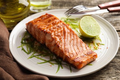 Photo of Delicious grilled salmon fillet served on wooden table, closeup